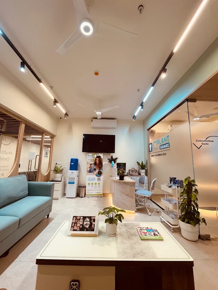 Implant Square Dental reception with teal sofa, coffee table, marble reception desk, and glass partition labeled Consultation Suite with clinic branding.